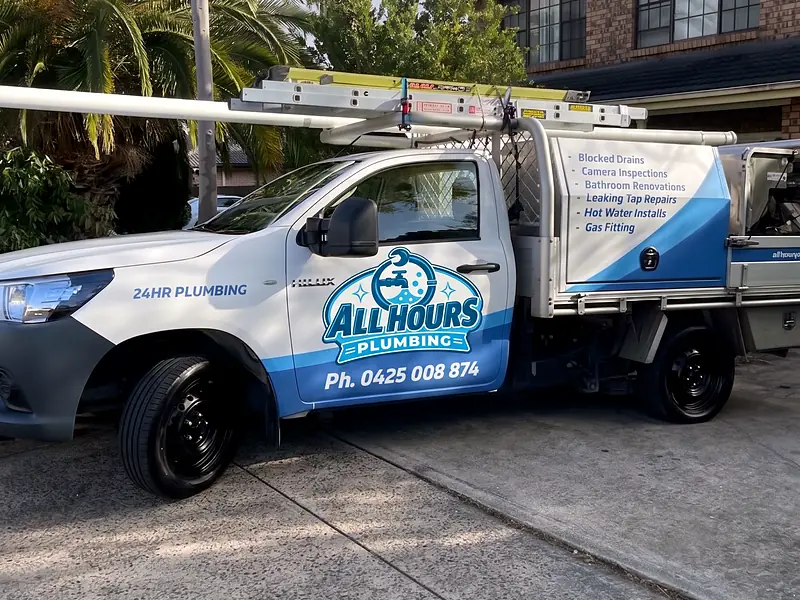 All Hours Plumbing ute with ladder rack and service signage parked in a residential driveway