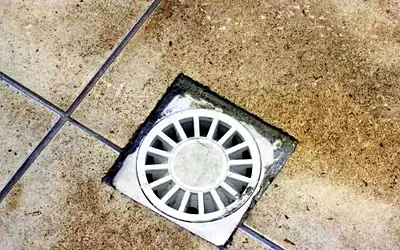 Round floor waste grate set into floor tiles
