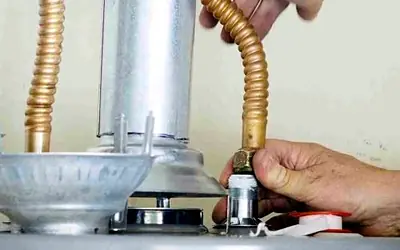 Hands tightening a gas connection on a hot water system