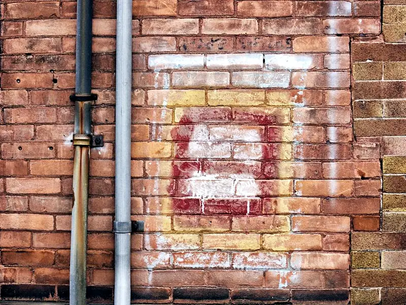 Metal downpipes running down a brick wall