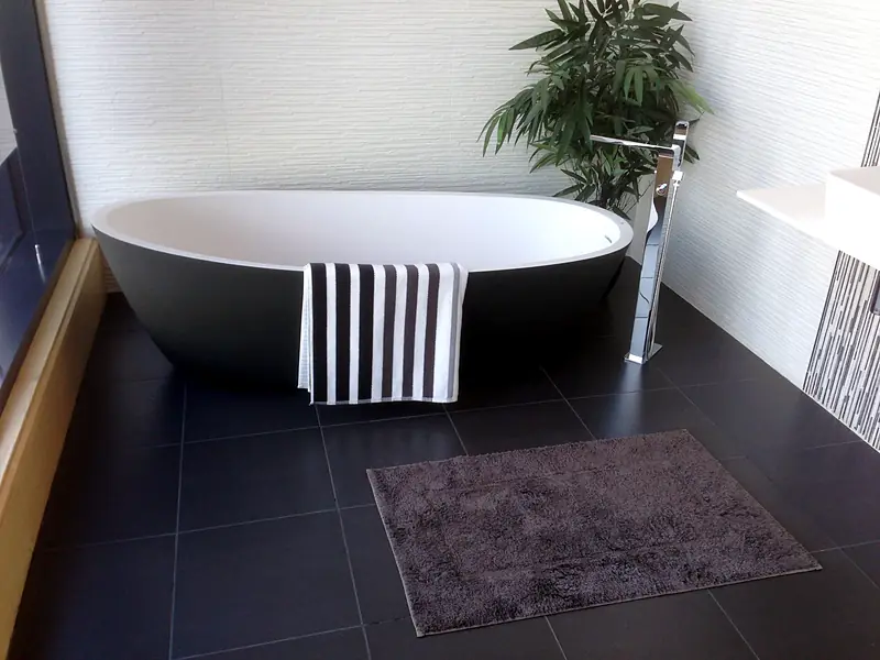 Freestanding bath with a floor-mounted mixer tap in a tiled bathroom